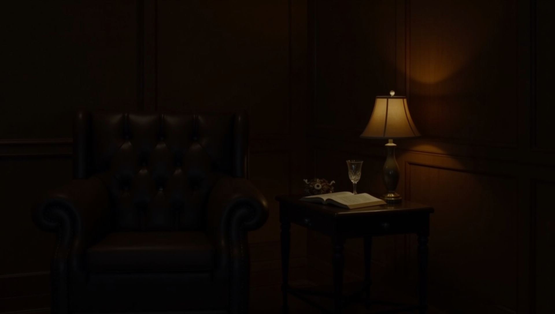 A leather armchair, closed book and crystal glass in a dark panelled room